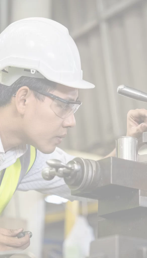 Plastics manufacturer with a white construction helmet working intensely on a machine.